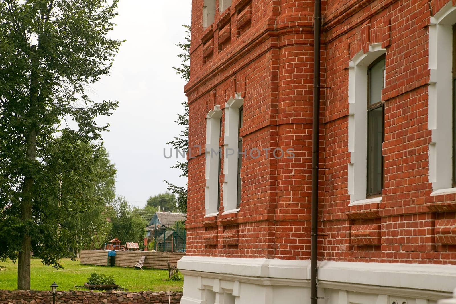 A large red brick building that features white trim along its edges and numerous windows, creating an inviting and charming appearance