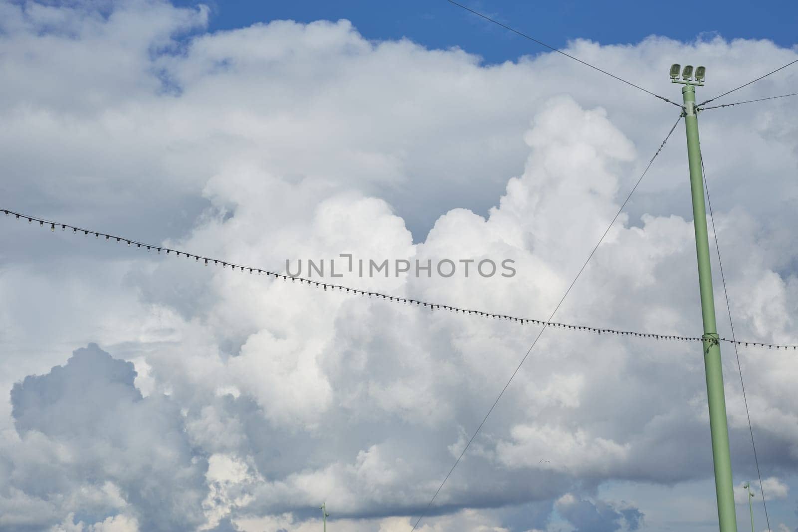 cloudy blue sky with light bulb garlands between the pillars