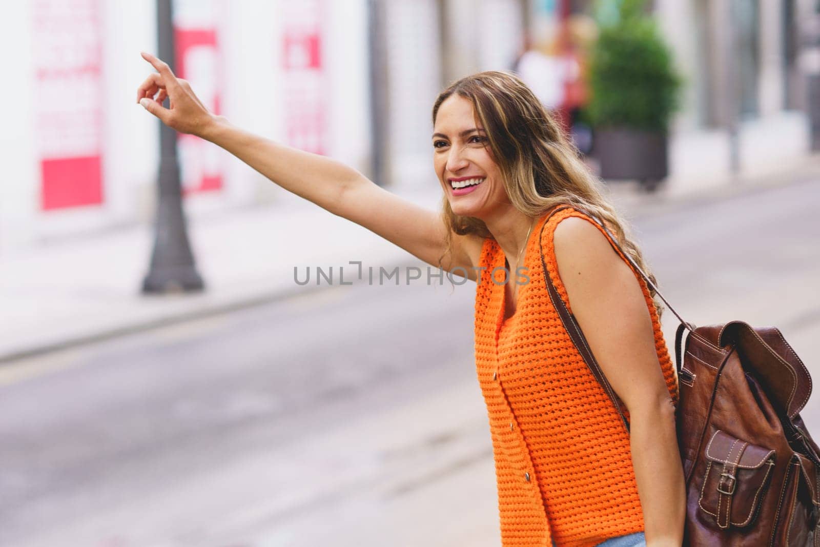 Latin beautiful smiling woman waving to catch a taxi in the city