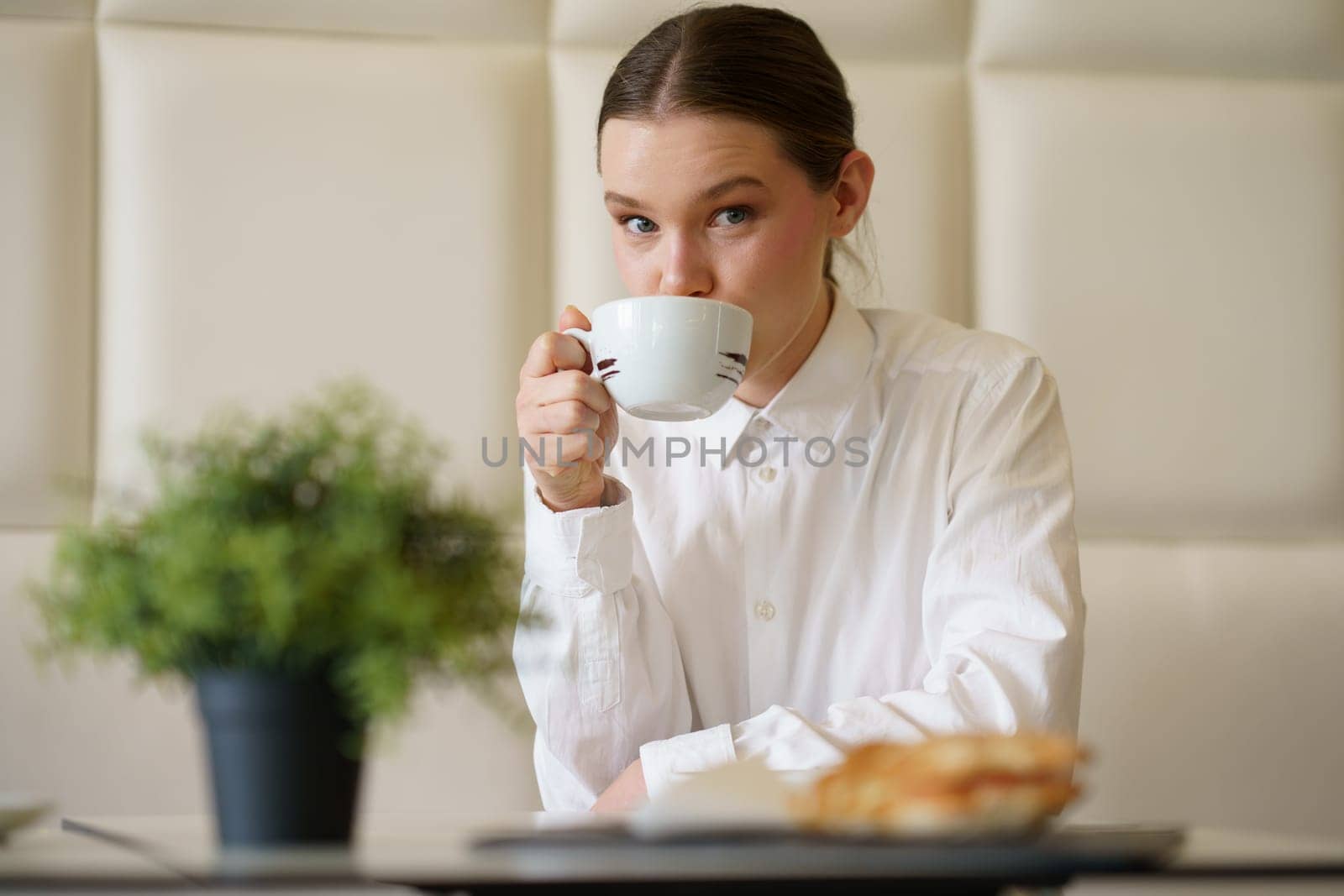 Beauty elegant woman looking at camera while drinking coffee in a cafeteria