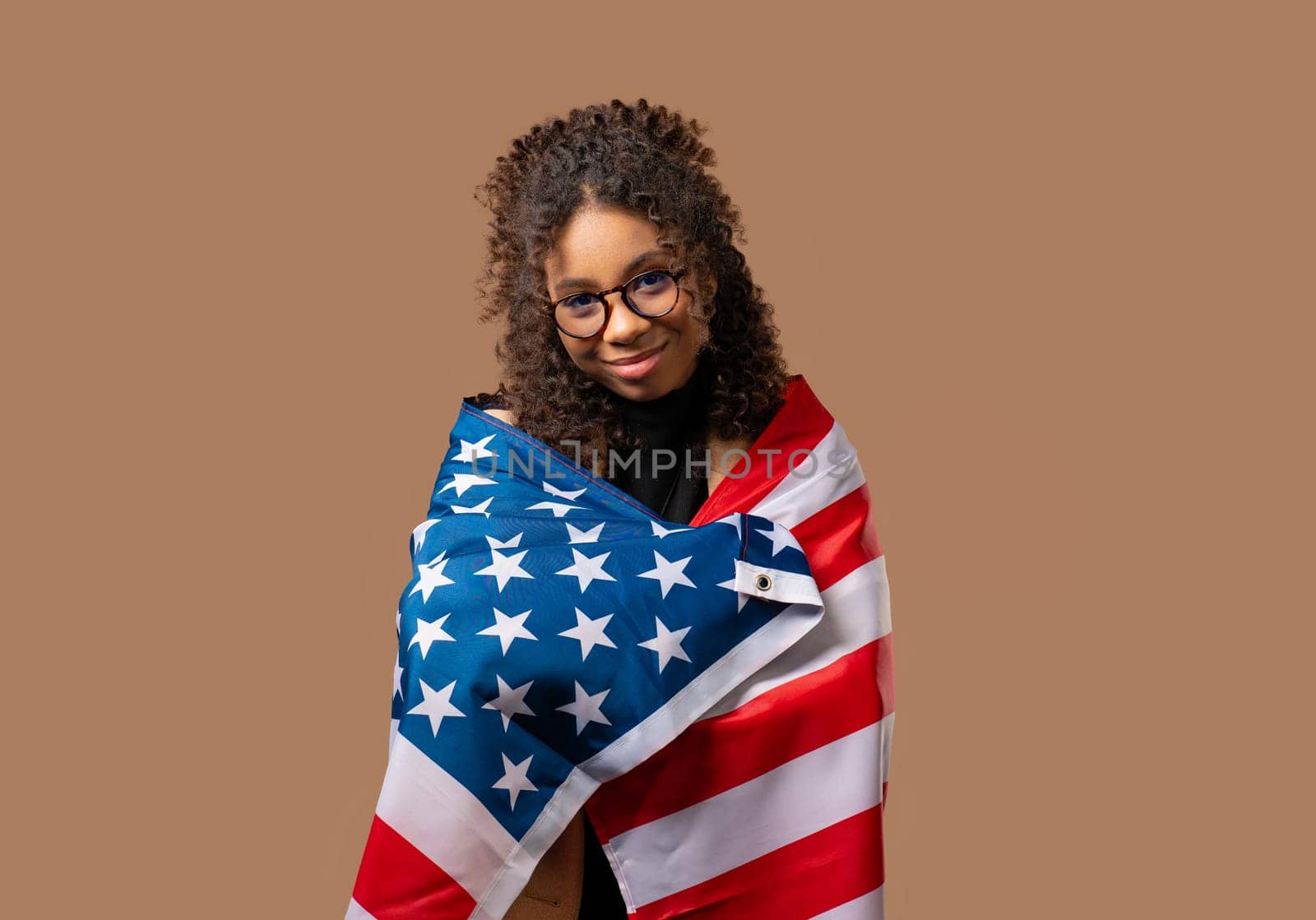 Smiling african american woman with national USA flag on beige background. American patriot, 4th of July - Independence day celebration, election, America, labor. US banner. High quality