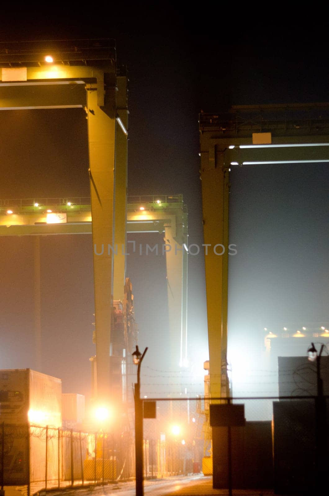 container terminal in industrial port with cranes. Sea port container terminal during work at night in fog. High quality photo