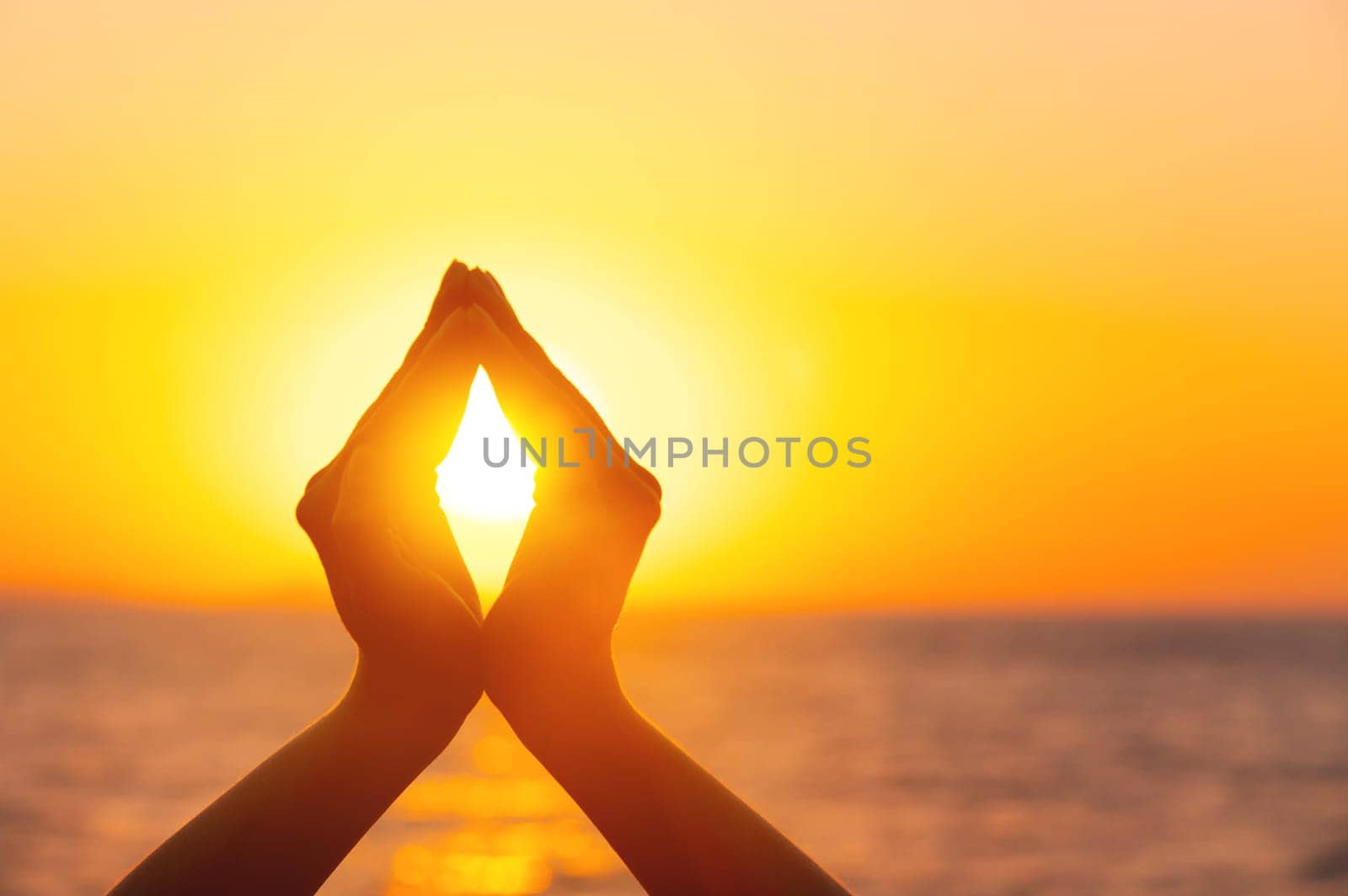 A woman's hands hold the sun at dawn. Freedom and spirituality concept. Sunset against the background of raised female hands.