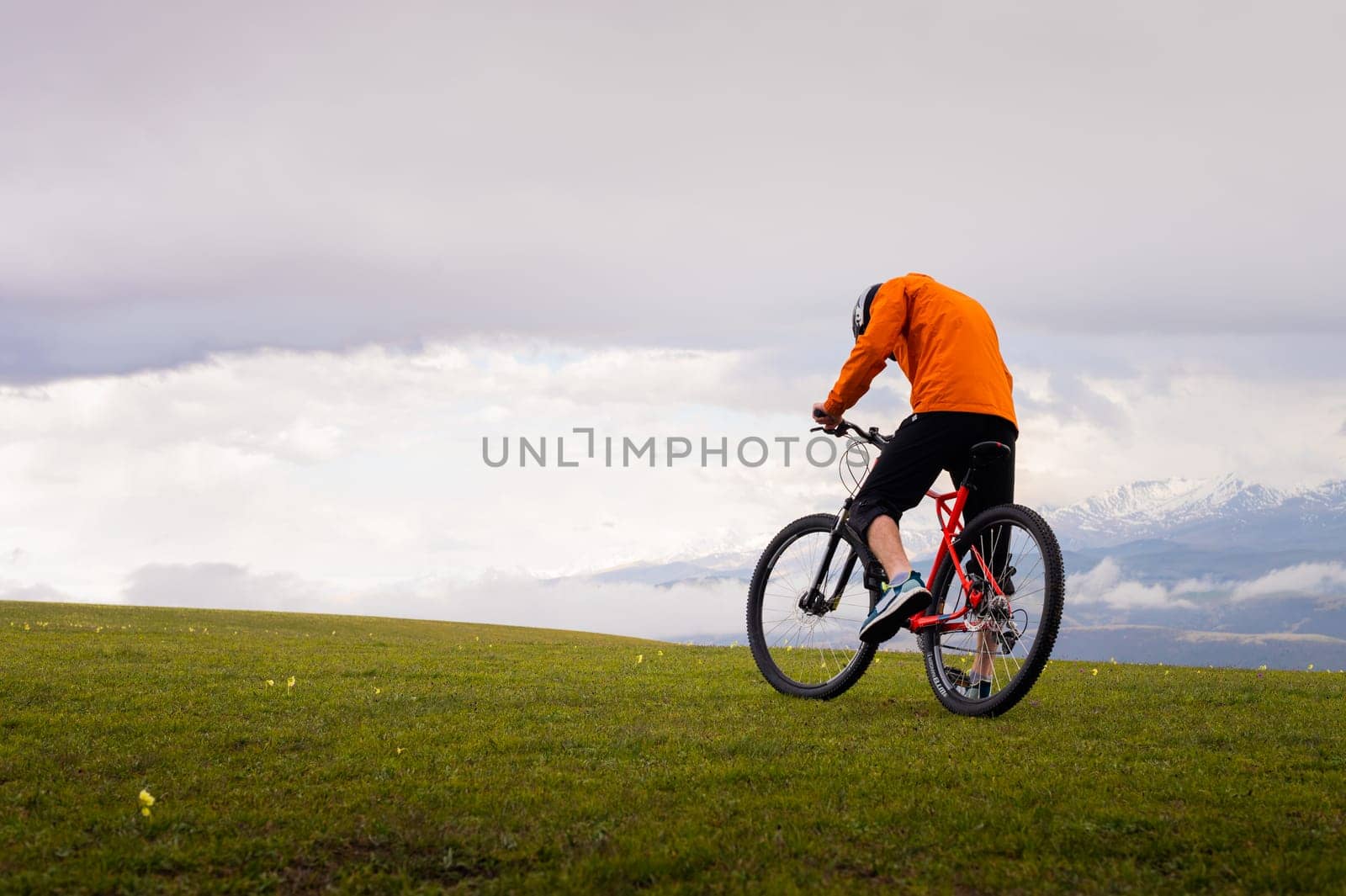Professional mountain biker on the background of mountains and green hills. Tired mtb rider in full face helmet outdoors by yanik88