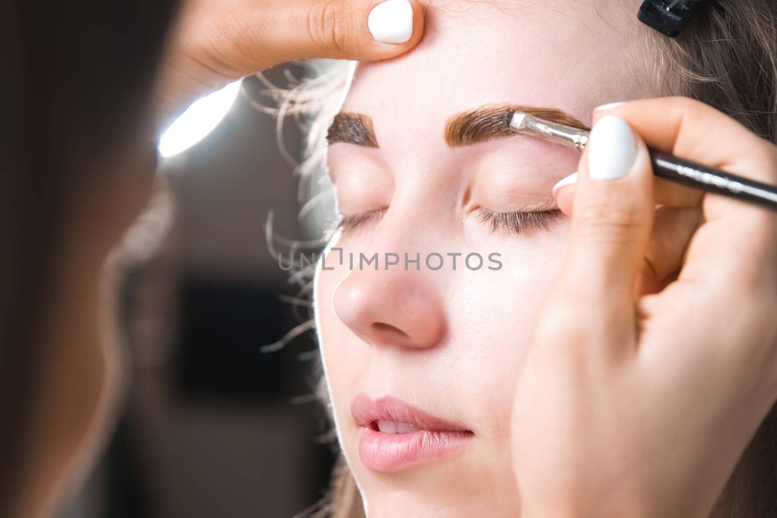 Eyebrow tinting. Close-up of a master applying eyebrow dye with a brush. Cosmetic procedures, permanent eyebrow makeup. correction and modeling of eyebrows in a beauty salon by yanik88