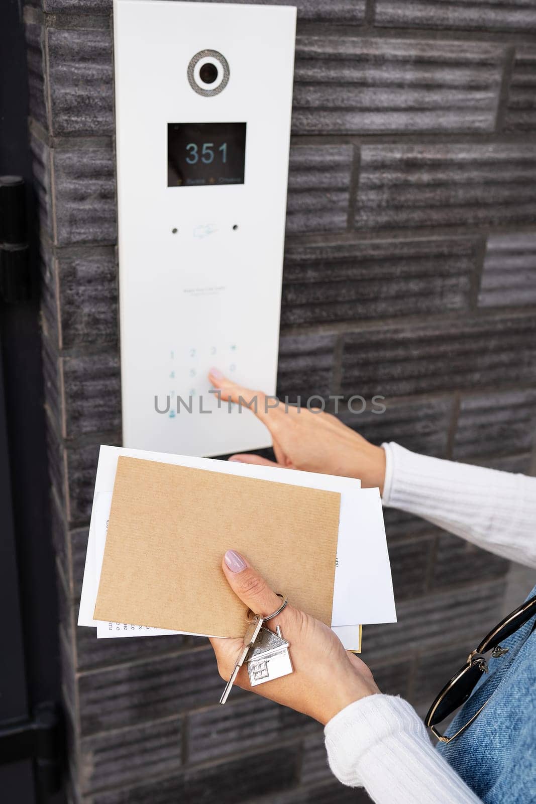 Door Access Control - A young woman, holding her mail in her hands, enters the code to open the door. Code door. by sfinks