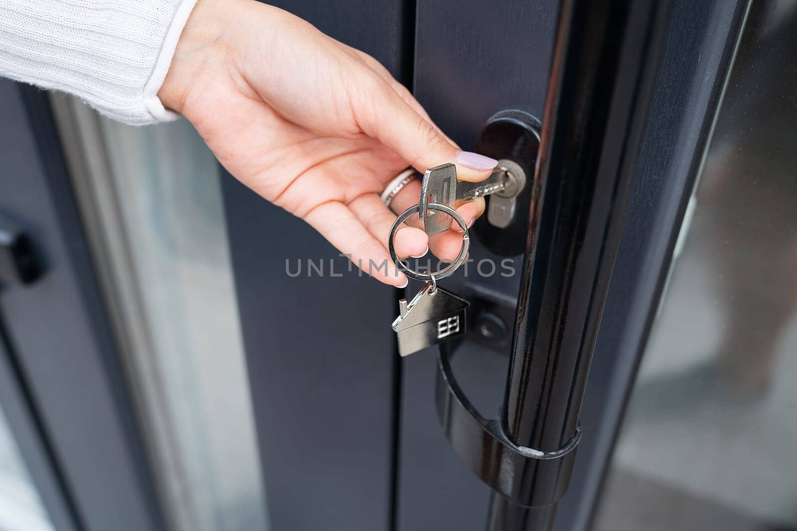 A woman's hand opens the door with a key on which the keychain hangs at home and copies the space