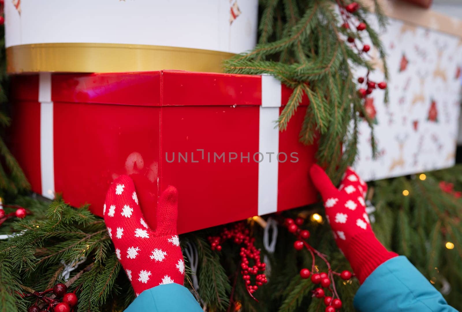 A girl in the street in red mittens holds a large red box in her hands. Christmas and New Years Eve