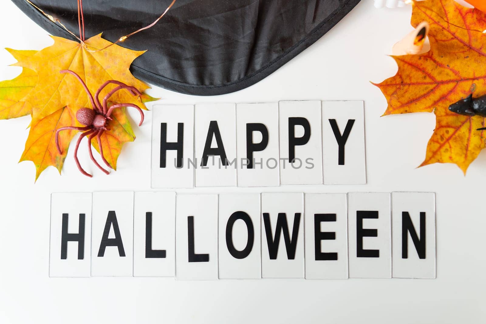 Happy Halloween lettering isolated on white background, holiday and party concept. Against the background of a spider, a mouse, a hat, yellow leaves