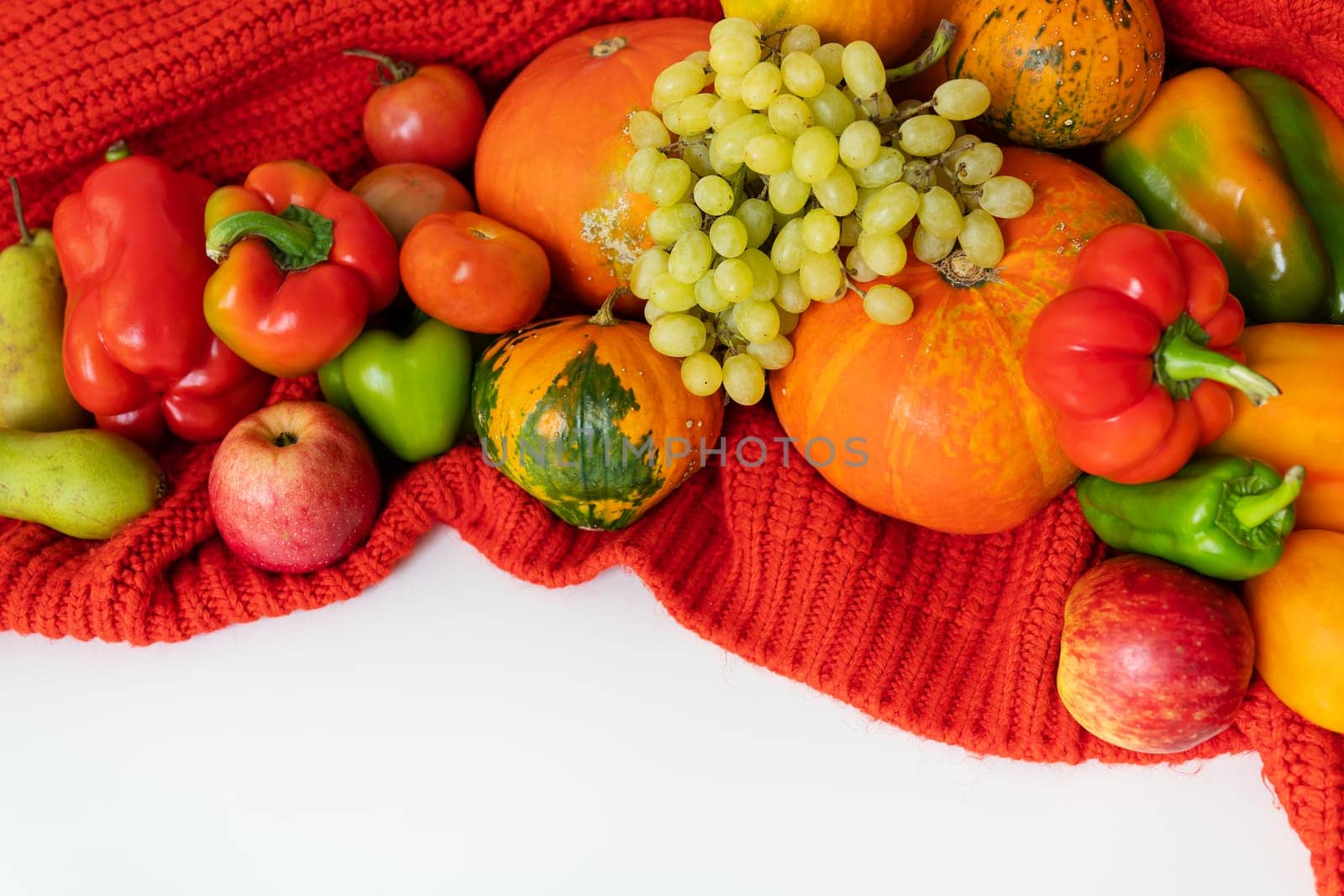 Thanksgiving Day. Big autumn harvest - pear, apples, pumpkin, pepper, tomato on a white background and red cloth. Thanksgiving celebration concept, top view