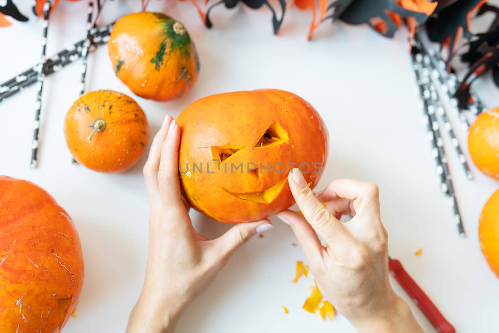 Halloween October 31st. The step-by-step process of carving a pumpkin. The girl cuts the face of the pumpkin with a knife. View from above