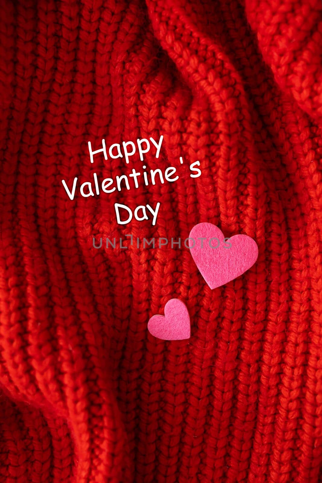Decorative pink heart on a red knitted background, top view. Lettering Happy Valentine's Day