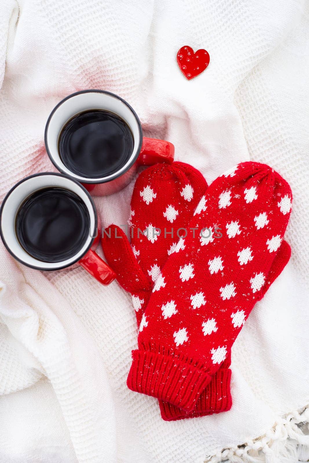 Romantic still life, two red cups of coffee on a white plaid together with red mittens. Valentine's day concept, card ready