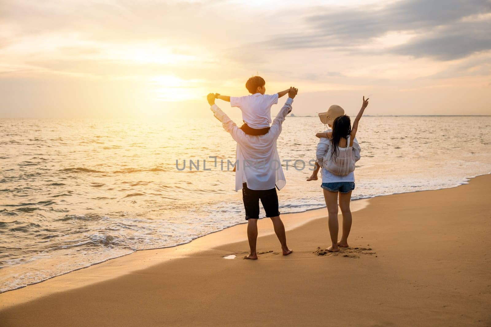 Happy family in holiday. Father, Mother and kids having fun together shoulder ride on summer beach, Parents carrying children on shoulders at beach on sunset time, Family on holiday summer vacation