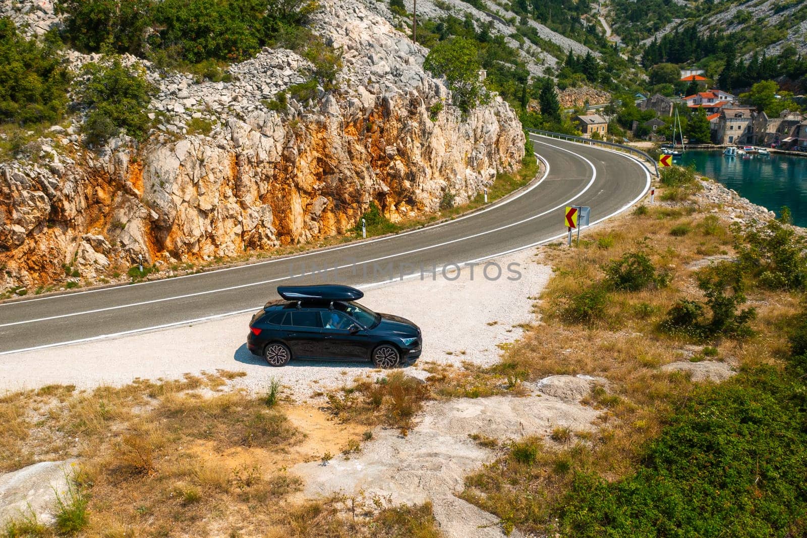 Car with a roof box stands on the side of a cliff and beautiful rocks in the background