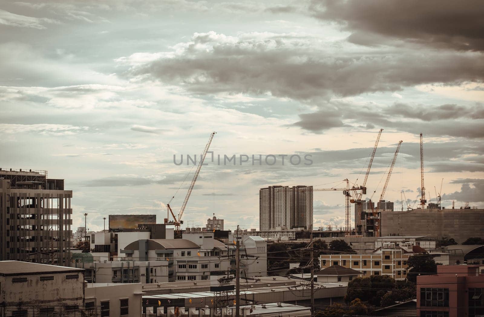 Bangkok, Thailand - Aug 14, 2024 - View of Construction of tall buildings with a crane and background of Dramatic sky in the city of Bangkok. Tower crane, Construction cranes, Construction and urban development. use it as your Wallpaper, Poster and Space for text, Selective focus.