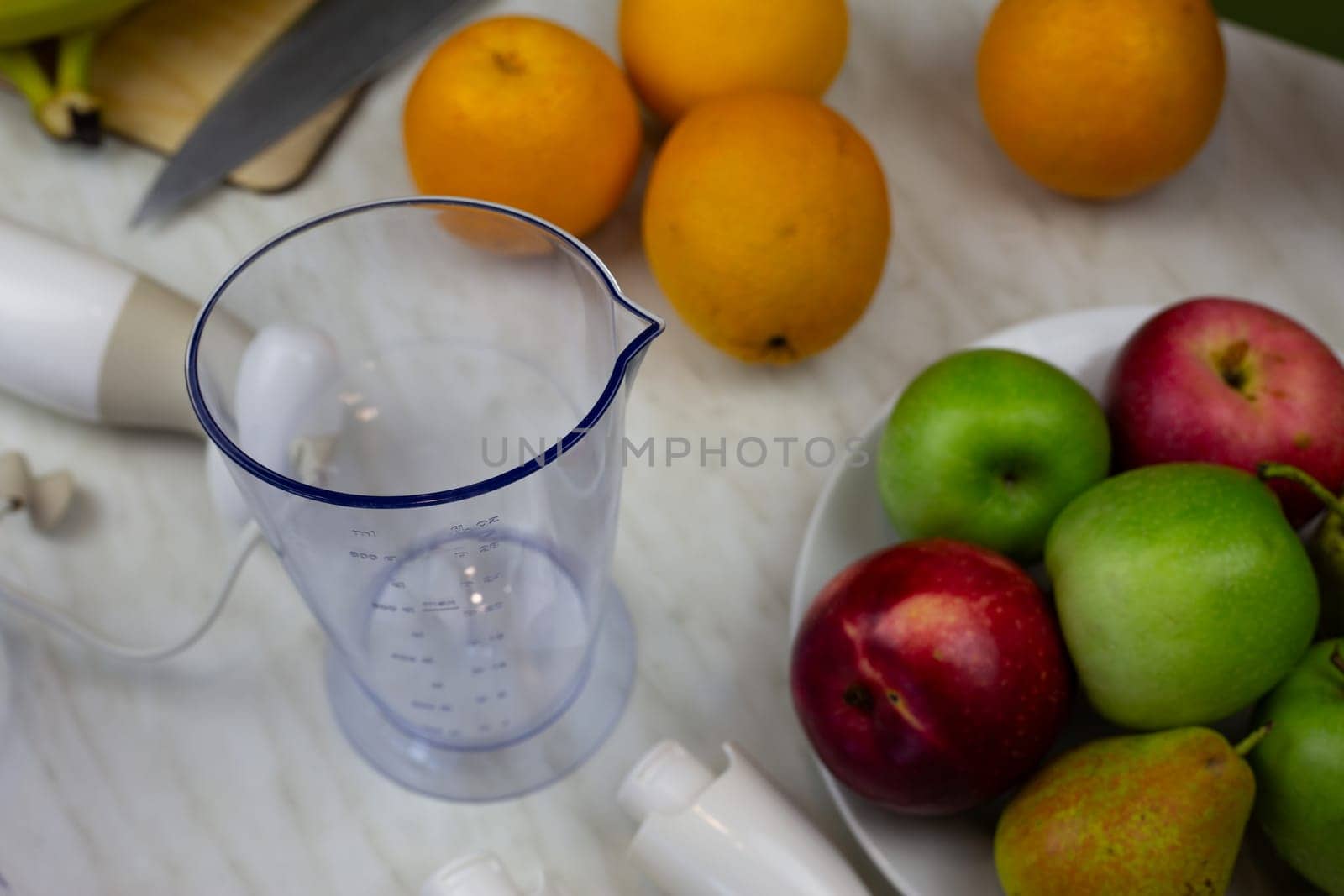 Measuring cup for making sports fruit cocktail on the table. Bowl for chopping fruits with blender when preparing healthy drink with vitamins for immunity
