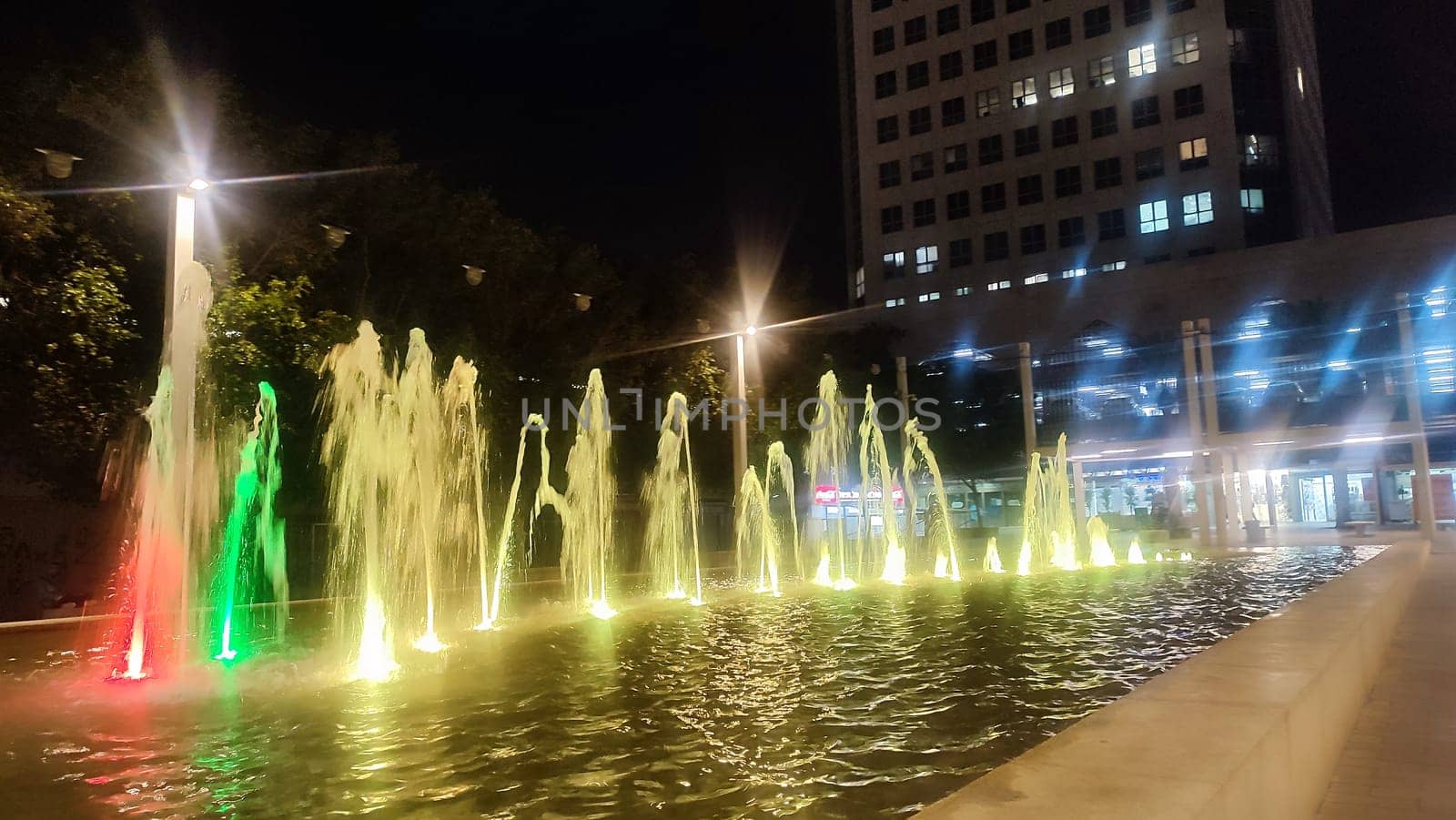fountains in the city, water with multi-colored illumination, street at night light . High quality photo