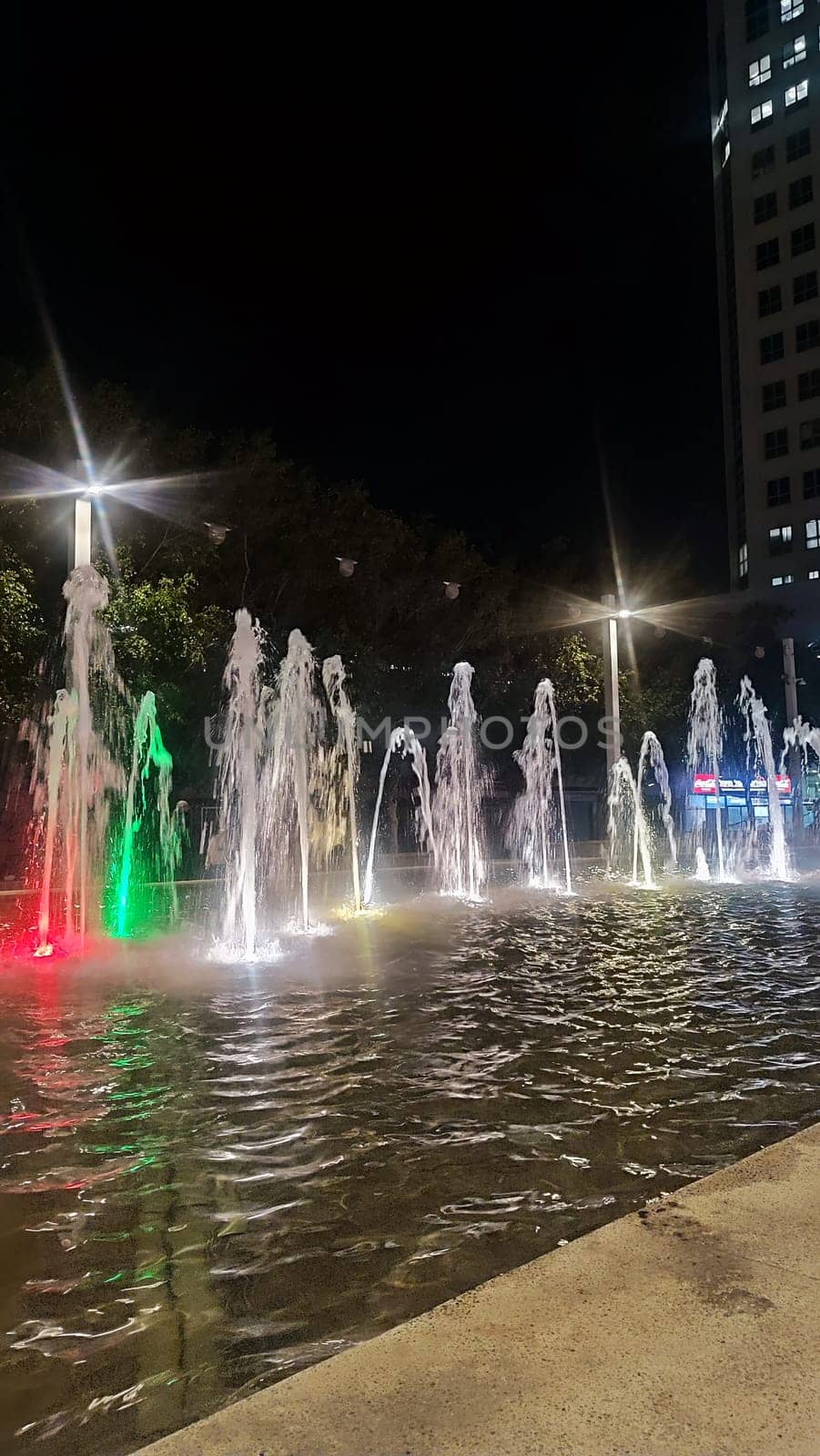 fountains in the city, water with multi-colored illumination, street at night light . High quality photo