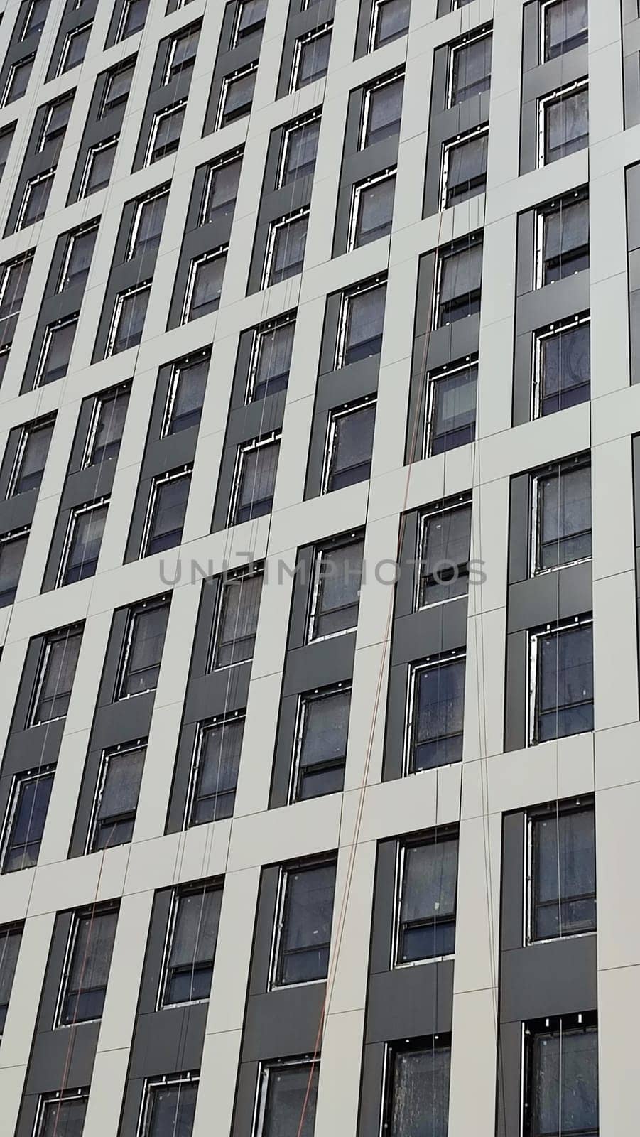 construction of a high-rise gray building, windows office building, city object, blue sky . High quality photo