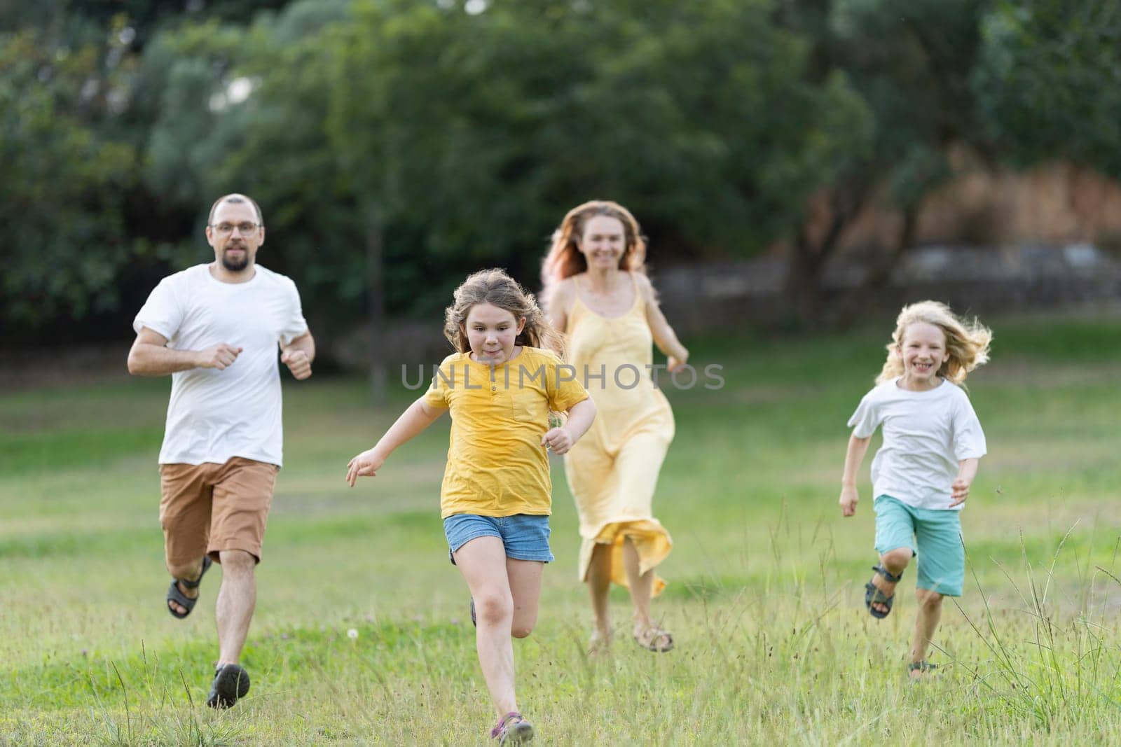 Family is running together through a grassy field on a sunny day