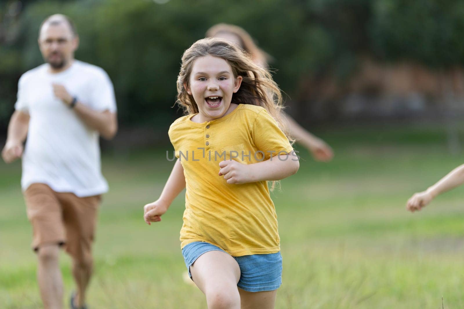 Family is running and playing together in a park, enjoying their free time