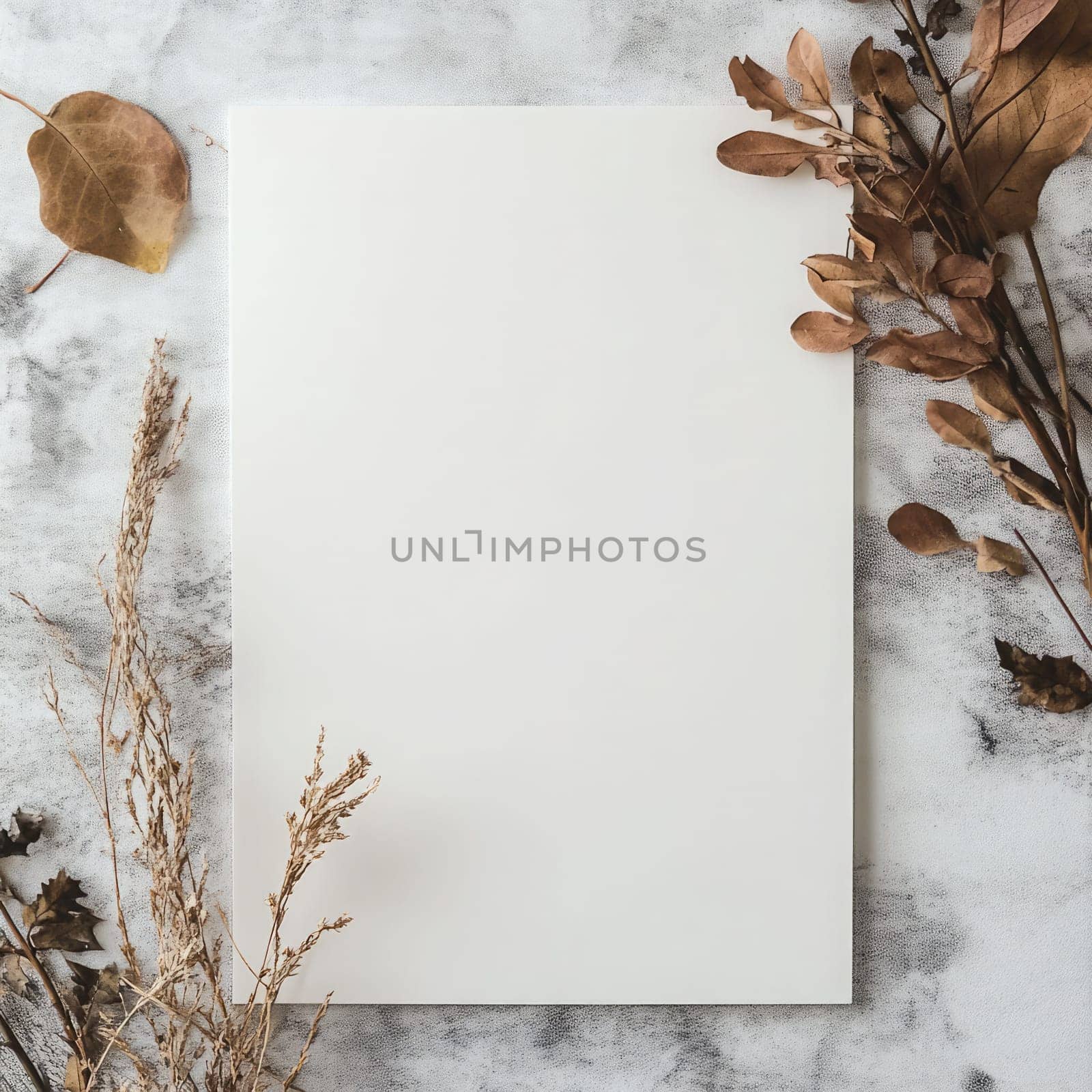 A piece of blank paper lies on a textured fabric backdrop surrounded by delicate dried flowers, creating an inviting space for writing or artistic projects.