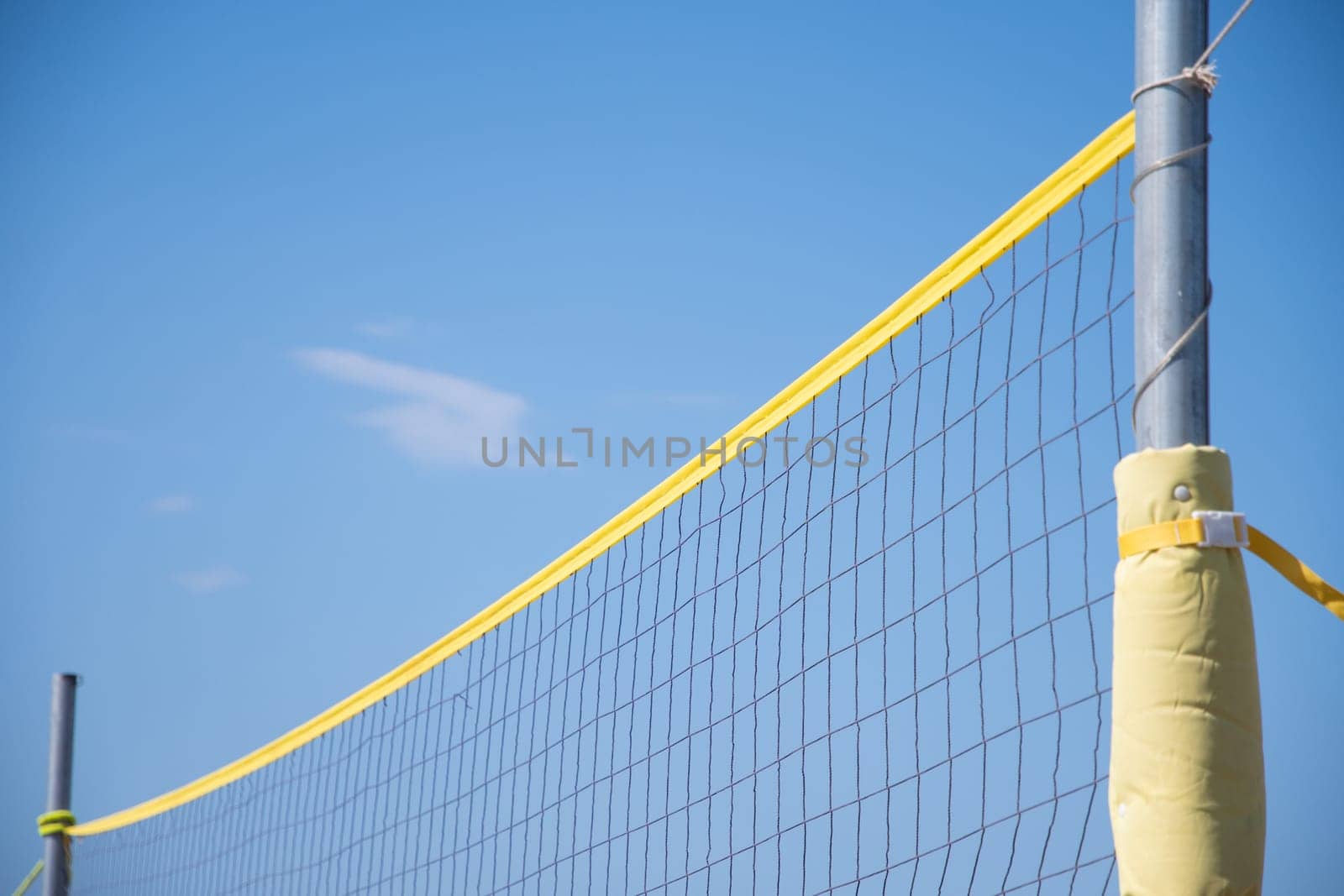 the ball flies through the net against the background of a clear blue sky, beach volleyball in the sea or ocean in summer, ball matches and active activities, copy space