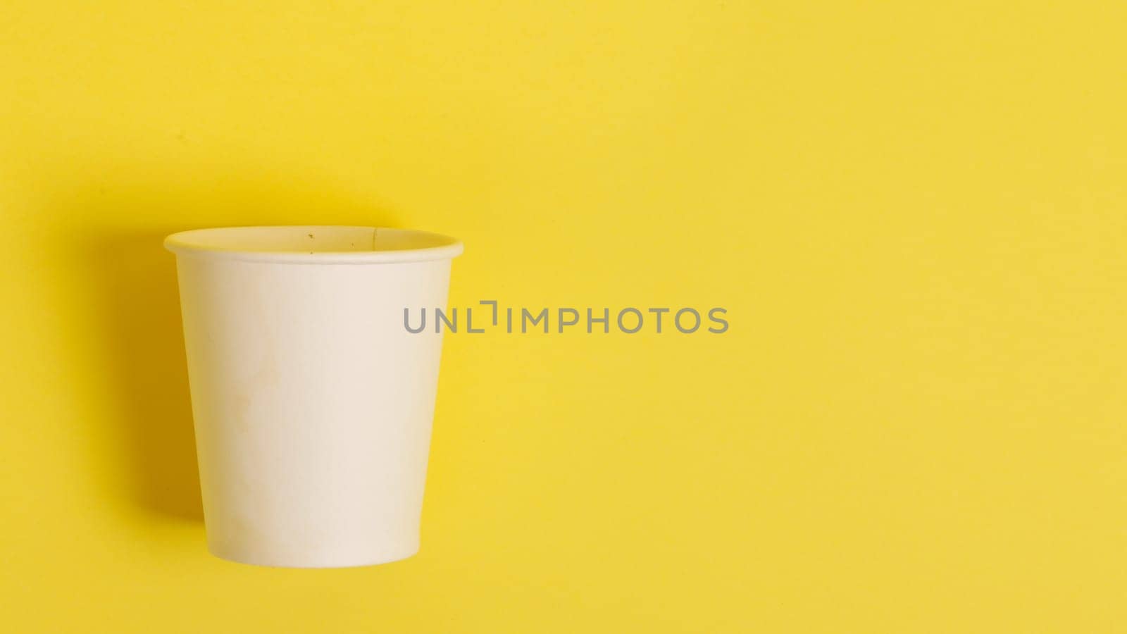The concept of environmental protection. Copy the space. Disposable paper cup for coffee and tea on a yellow-orange background. coffee break...