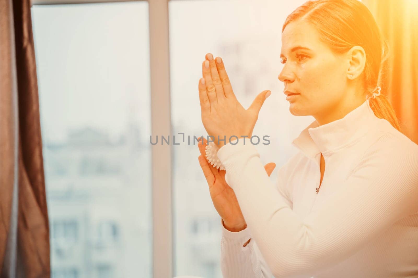 Athletic slim caucasian woman doing thigh self-massage with a massage ball indoors. Self-isolating massage.