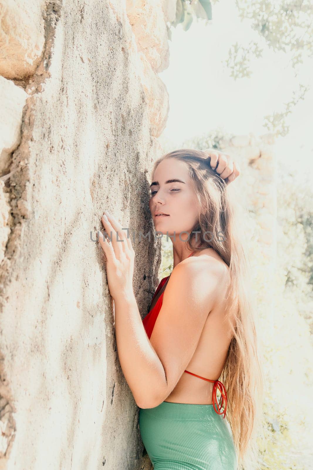 Woman travel sea. Young Happy woman in a long red dress posing on a beach near the sea on background of volcanic rocks, like in Iceland, sharing travel adventure journey