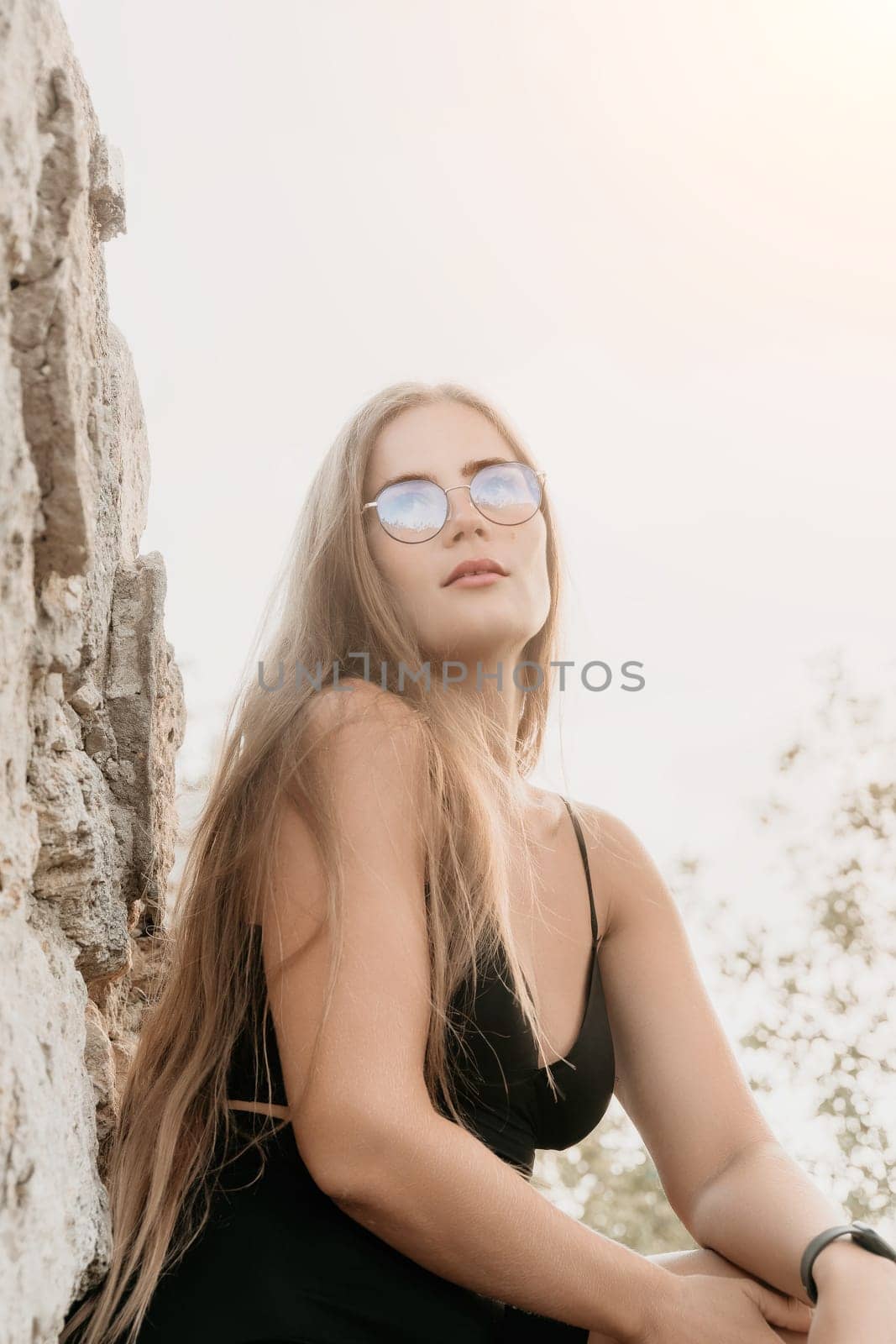 Woman travel sea. Young Happy woman in a long red dress posing on a beach near the sea on background of volcanic rocks, like in Iceland, sharing travel adventure journey