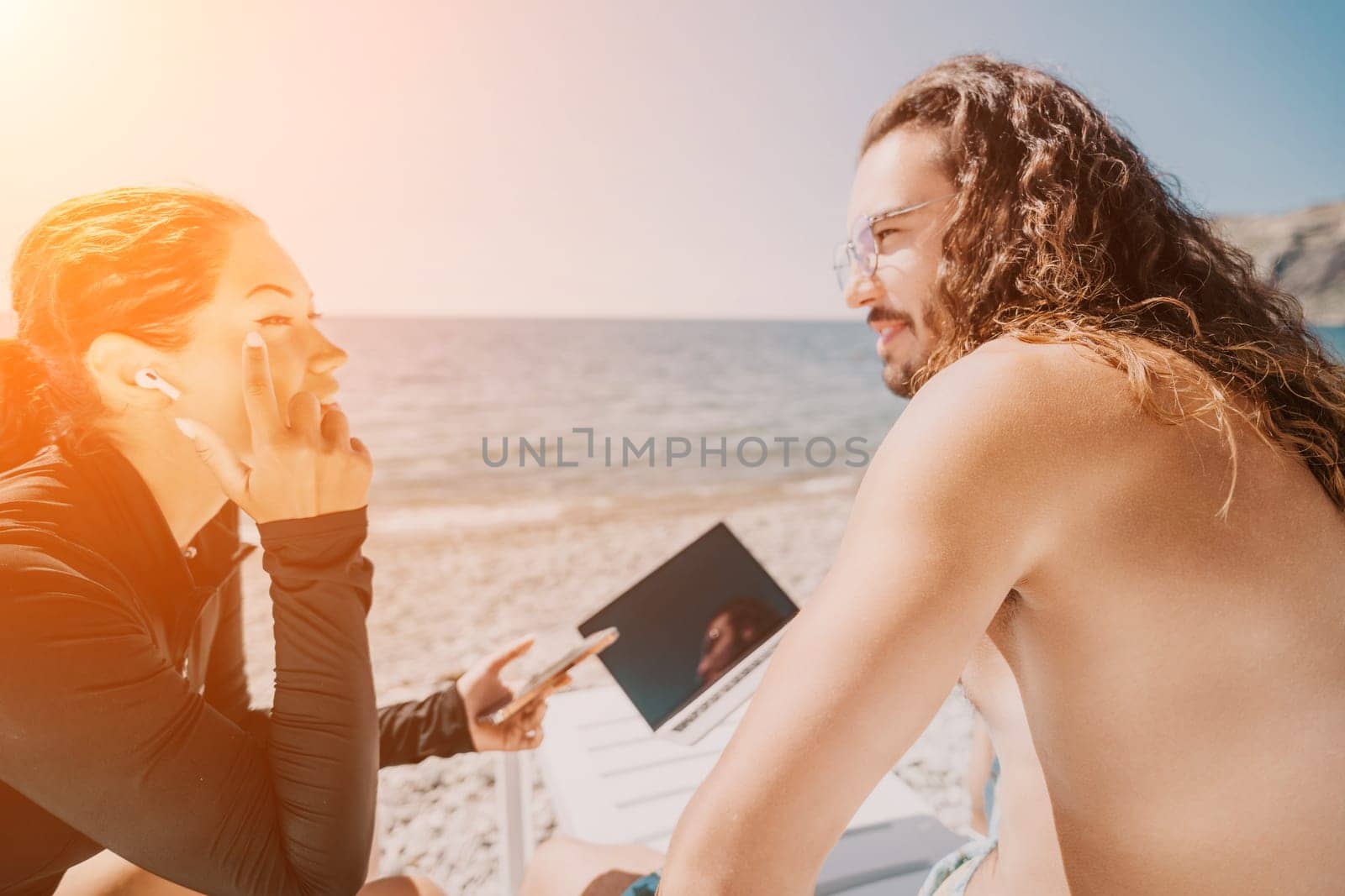 Digital nomad, Business man working on laptop by the sea. Man typing on computer by the sea at sunset, makes a business transaction online from a distance. Freelance, remote work on vacation