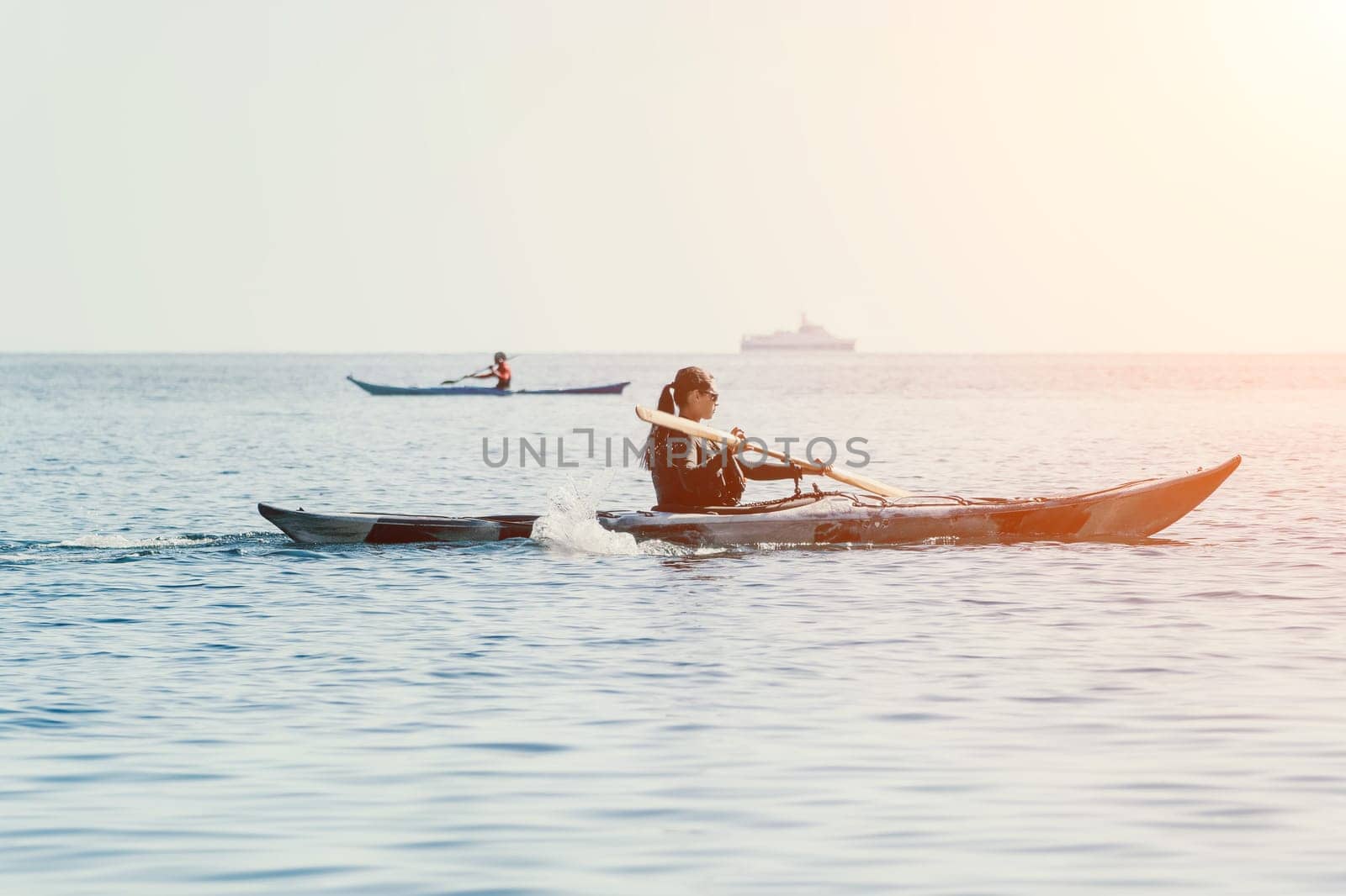 Happy smiling woman in kayak on ocean, paddling with wooden oar. Calm sea water and horizon in background