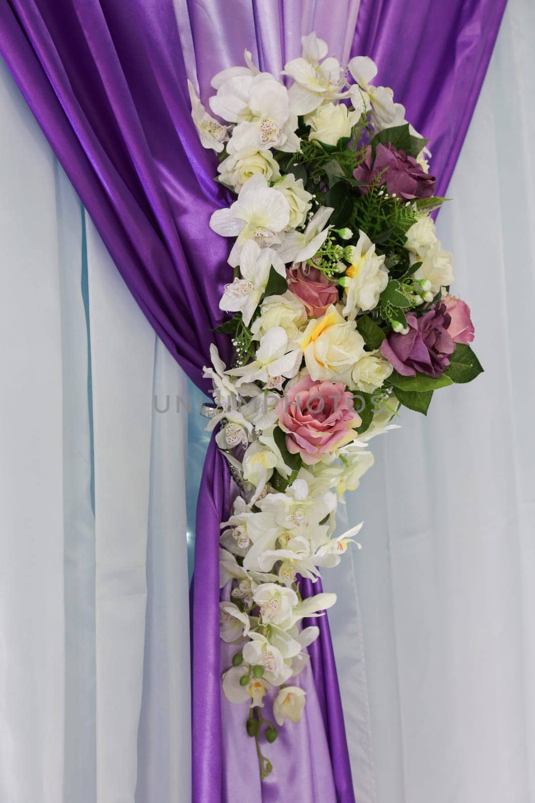 Backdrop curtain decoration. Multi-colored bouquet on a lilac and white curtain. Wedding decoration with flowers.