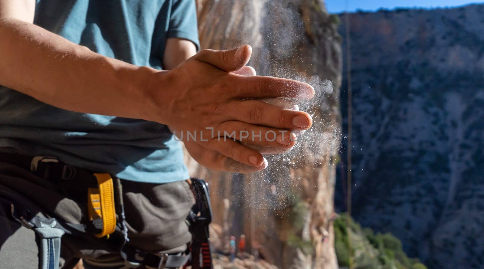 Male hands with magnesia powder close-up against the background of the mountains on a sunny day, the hands of a climber who prepares for outdoor training, a man is engaged in active sports in Greece.