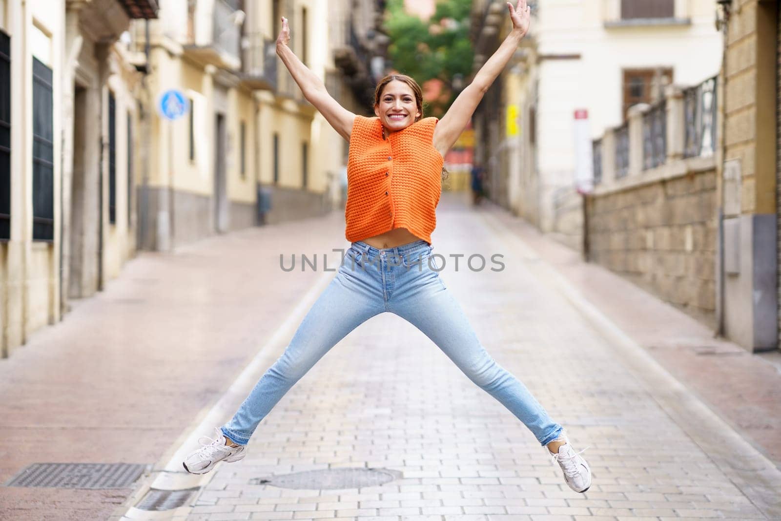 Full length portrait of a latin beauty woman celebrating freedom jumping in the city