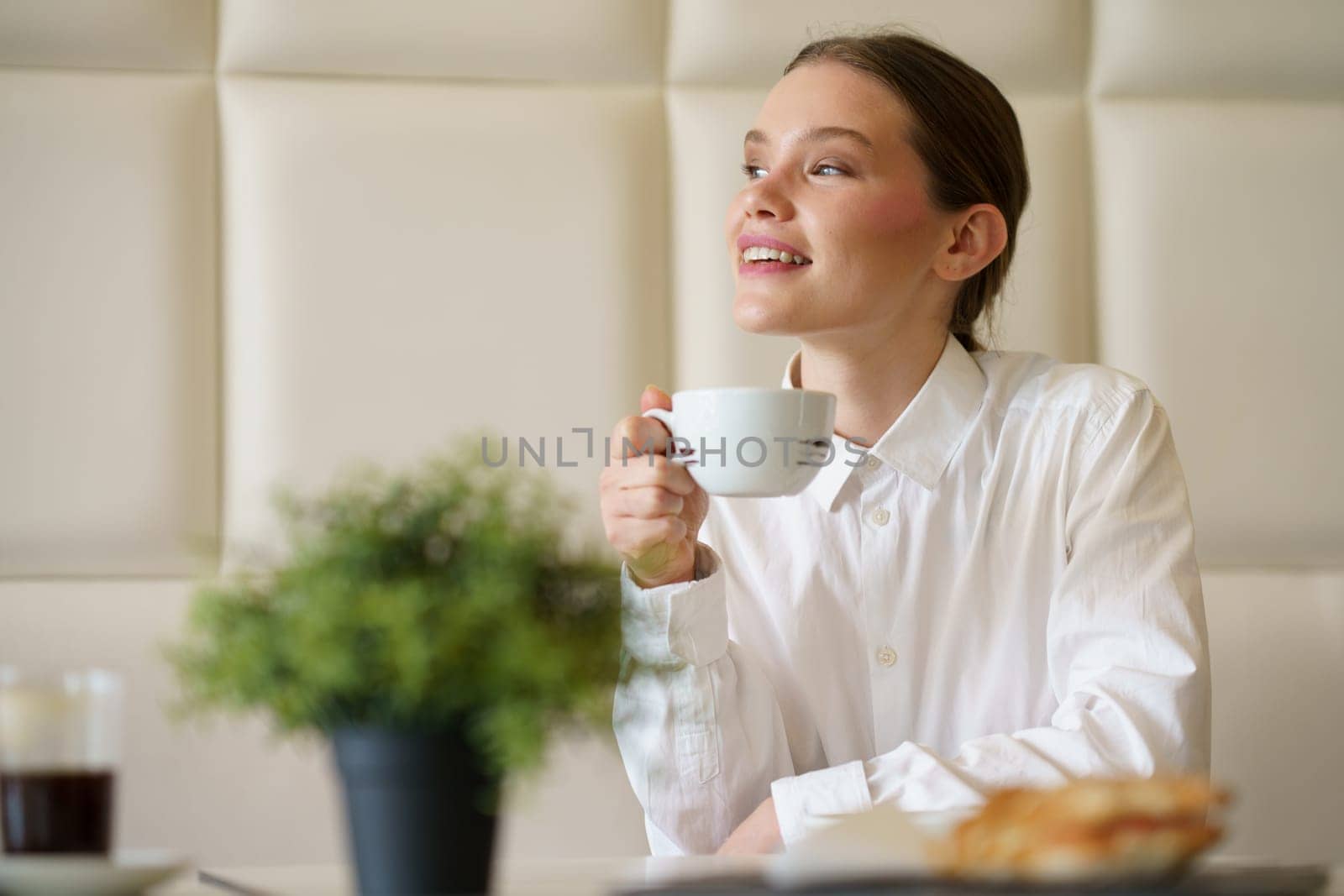 Happy businesswoman enjoying morning breakfast and coffee in a chic cafeteria
