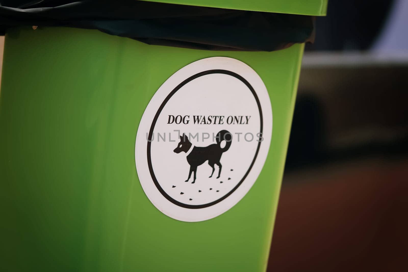 Waste management, green plastic bin featuring a white sign proclaiming its exclusive purpose for dog waste disposal, emphasizing environmental responsibility and the cleanliness of canine excrement.