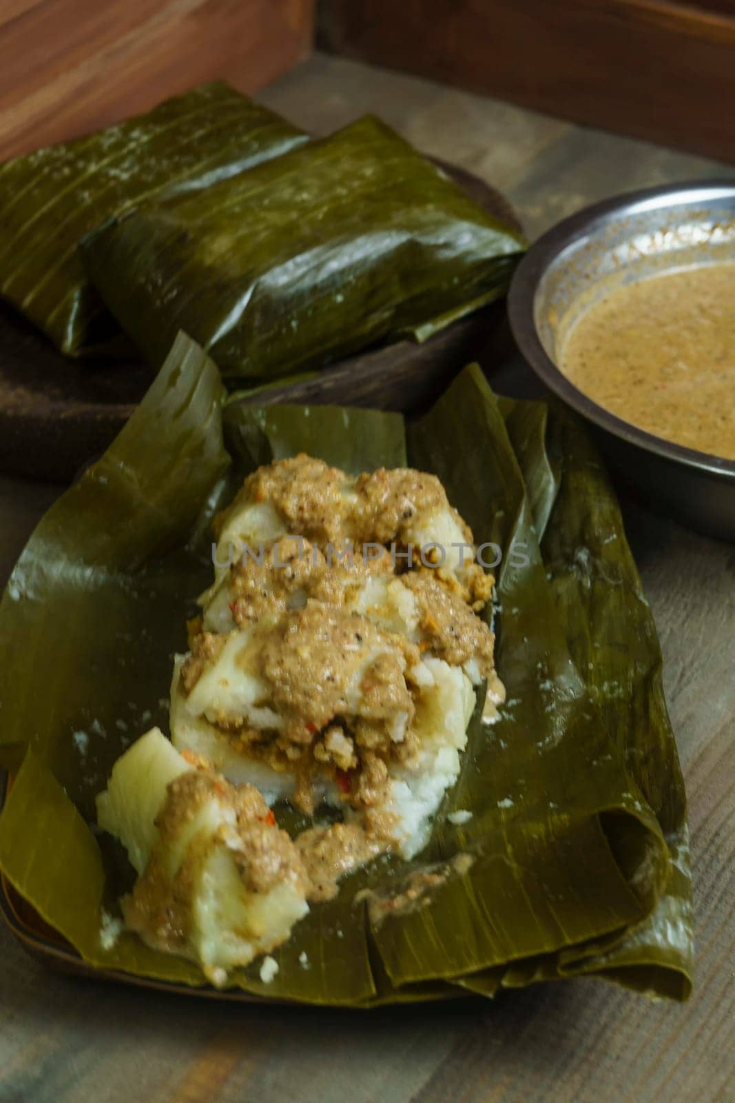 Lontong oncom, a traditional Indonesian dish with steamed rice cakes wrapped in banana leaves, served with spicy peanut sauce.