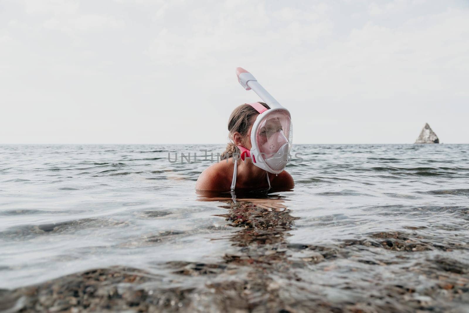 Young happy woman in white bikini put pink snorkeling mask on beach before swimming. girl having fun relaxing on beautiful beach. Beach lifestyle
