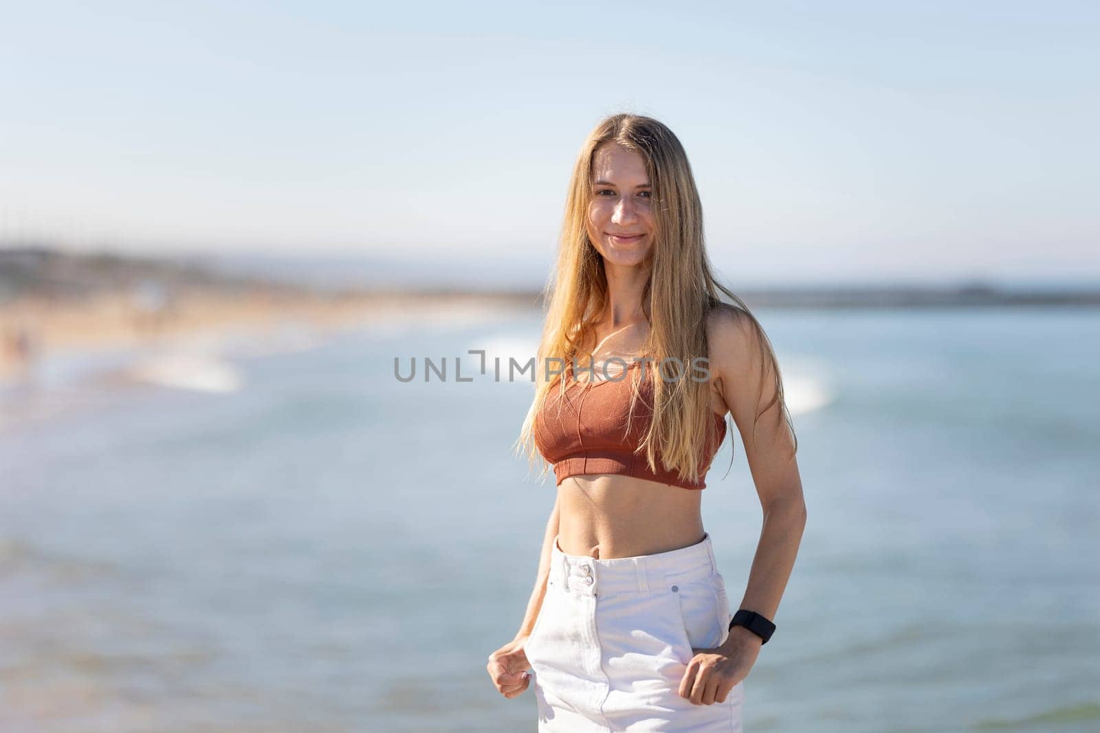 Young woman is standing on the beach with the ocean in the background