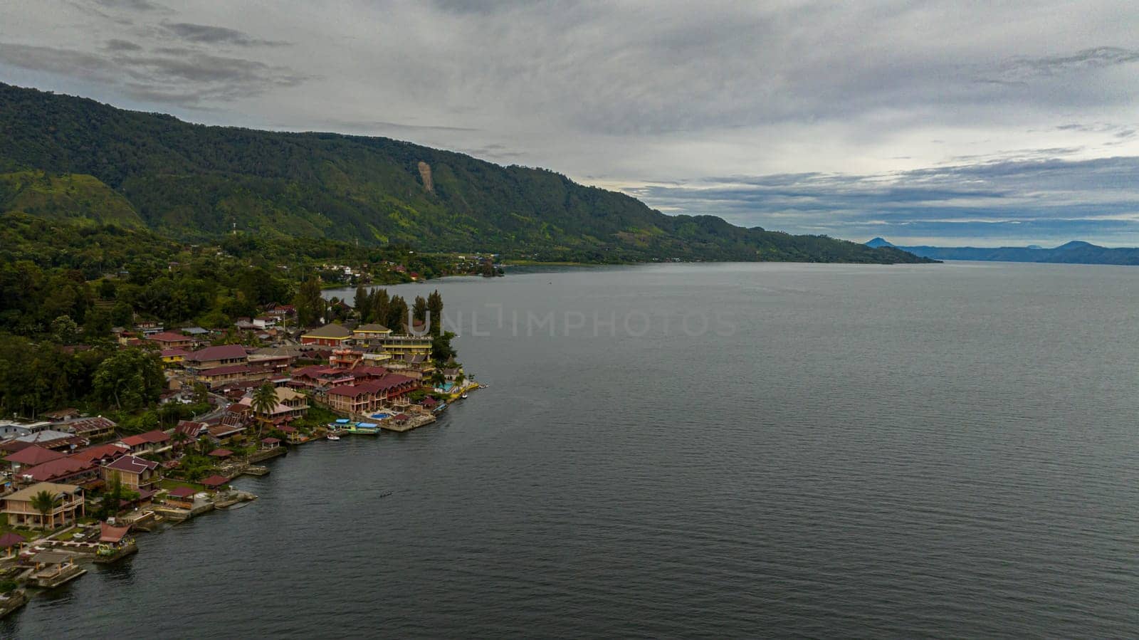 Aerial drone of Tourist spot Tuk Tuk on Lake Toba and the coast of Samosir Island. Sumatra, Indonesia. Tropical landscape.