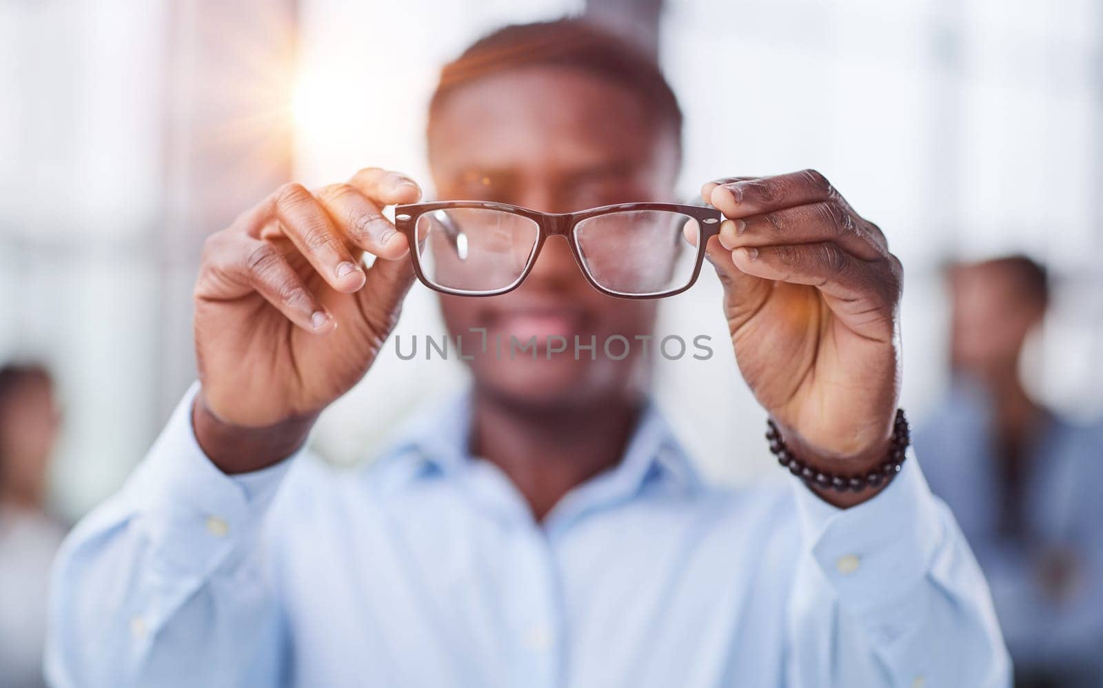 a black man in a blue shirt adjusts his glasses. by Prosto