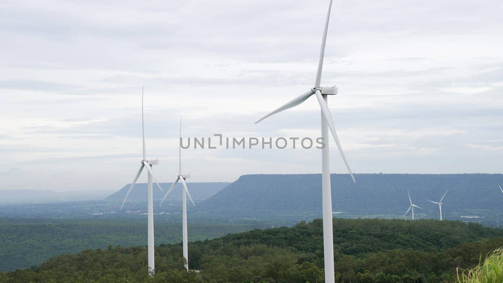Progressive way of utilizing wind as renewable source of energy to power the modern way of life by wind turbine farm on green field or hill. Windmill generator generate electric with no CO2 emission.