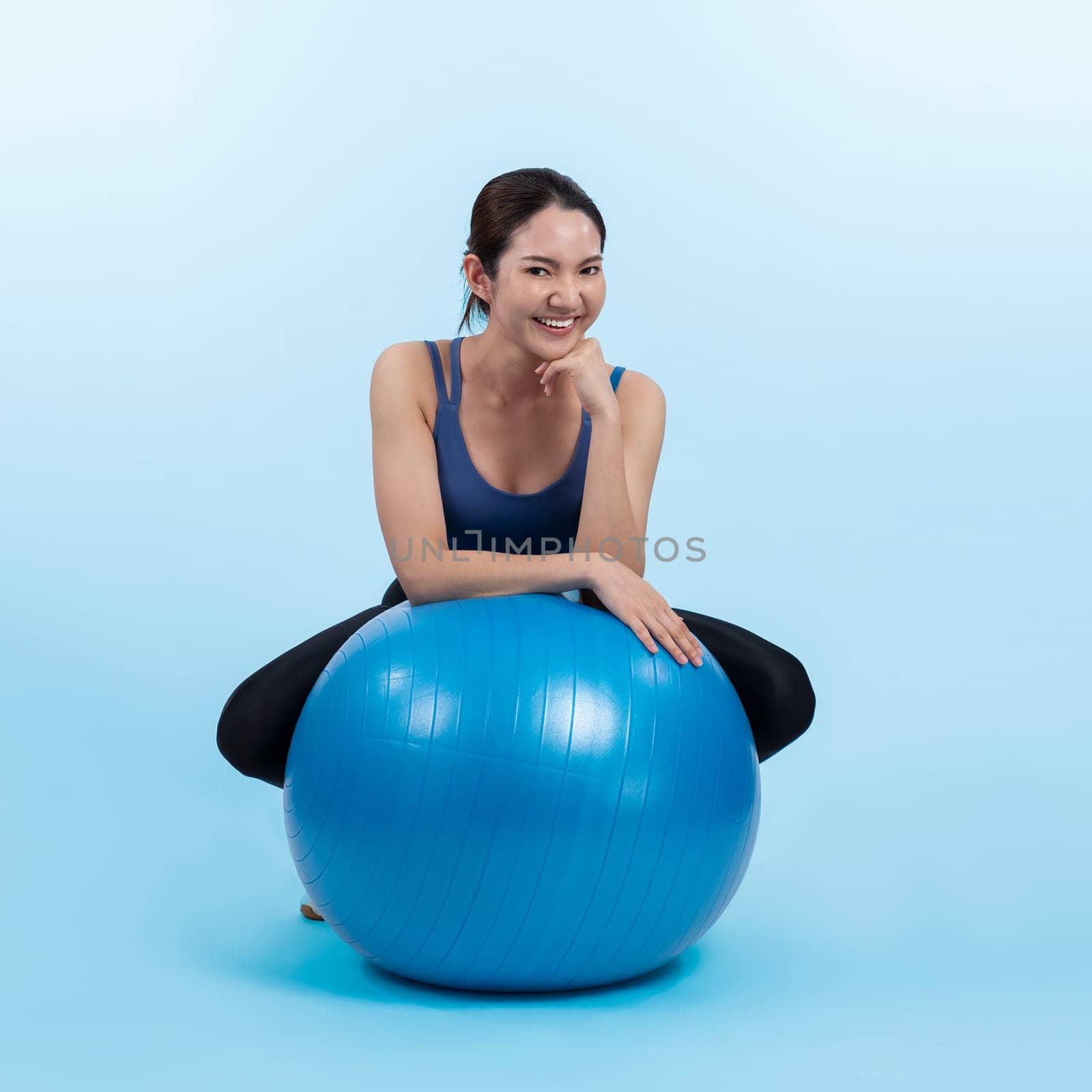 Young attractive asian woman portrait in sportswear with fit ball targeting on abs muscle for effective energetic daily workout routine. Studio shot and isolated background. Vigorous