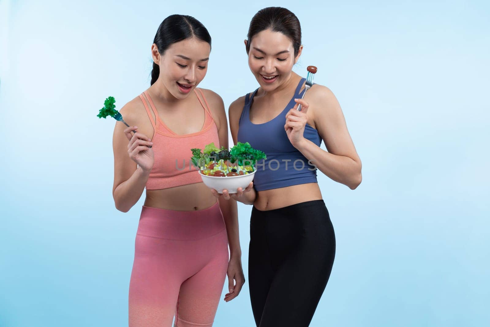 Asian woman in sportswear holding salad bowl on isolated background. Vigorous by biancoblue