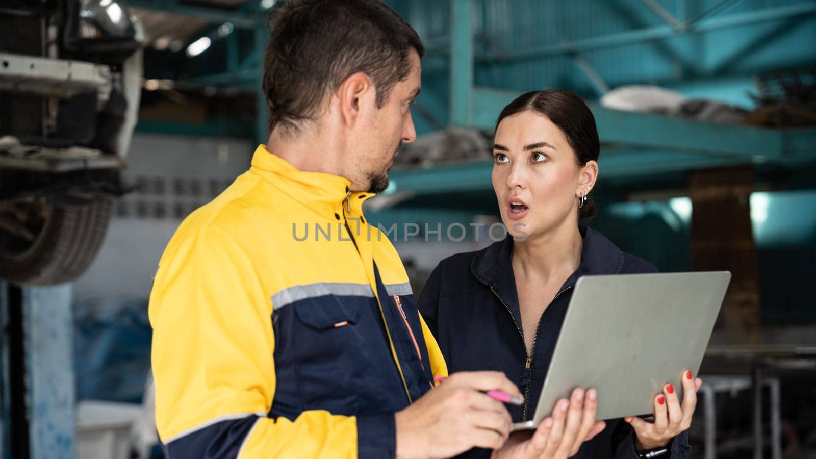 Two vehicle mechanic working together, conduct car inspection with laptop. Automotive service technician in uniform carefully make diagnostic troubleshooting to identify error. oxus