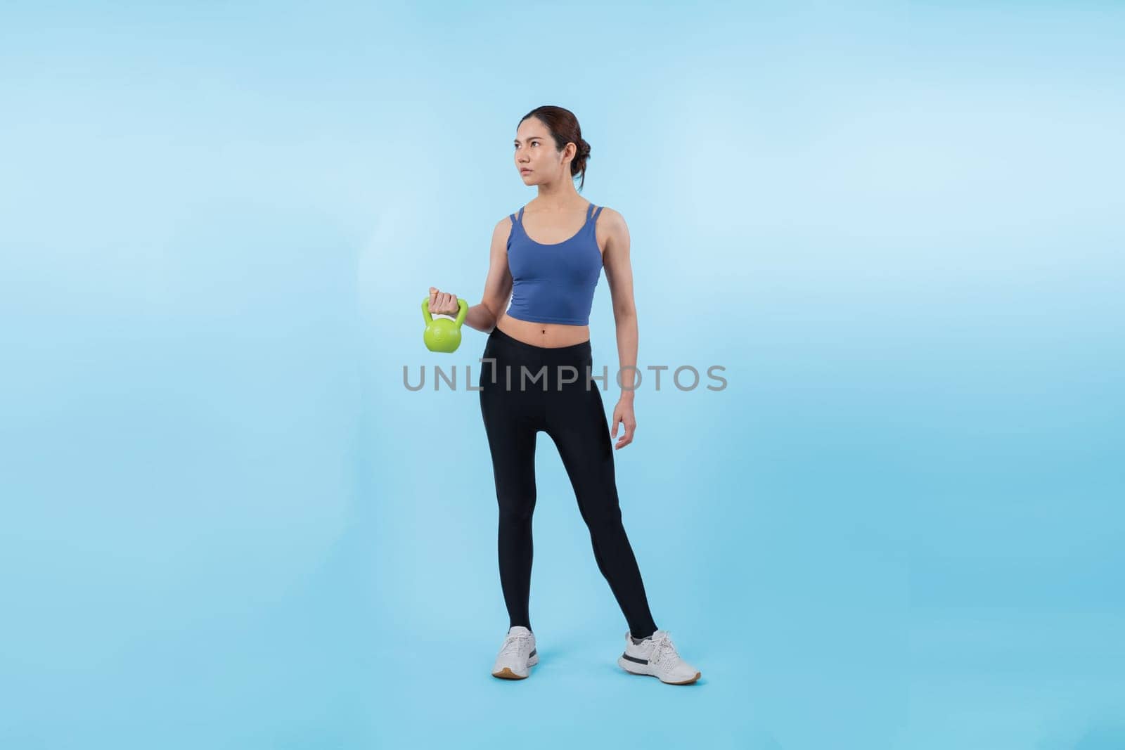 Vigorous energetic woman doing yoga with kettlebell weight exercise. by biancoblue