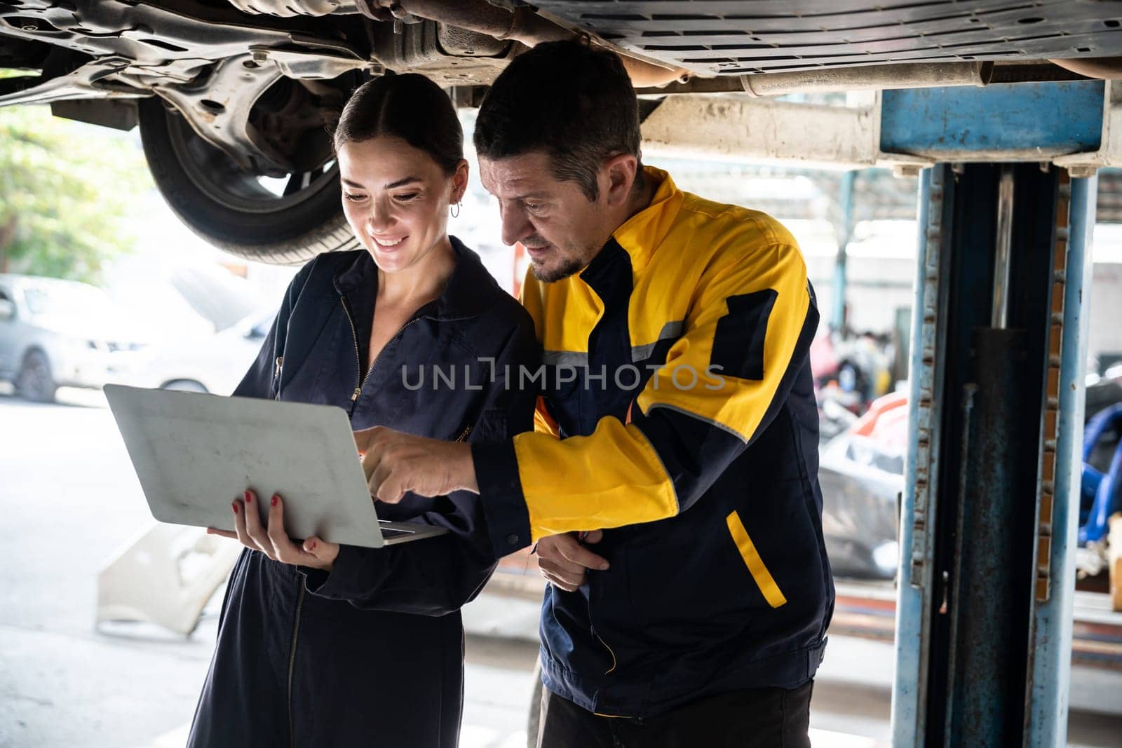 Two vehicle mechanic working together, conduct car inspection with laptop. Oxus by biancoblue